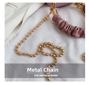 Close-up of golden beaded metal chain and soft pink pleated leather strap detail