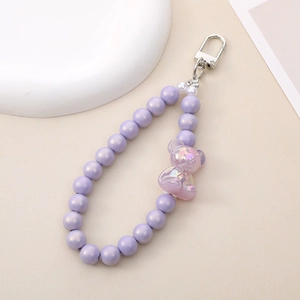 Detail of purple beaded keychain featuring a holographic bear charm and silver spring clasp