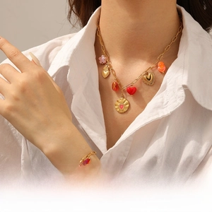 Detail of gold heart pendant necklace and bracelet set worn on a white shirt
