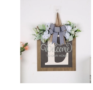 Detail of wooden welcome sign with letter L, faux white flowers and striped bow