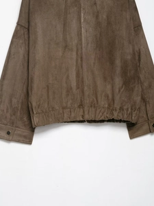 Detail of brown suede jacket hem showing elastic waist and metal snap on cuff