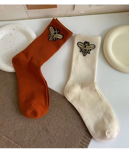 Close-up of knit socks featuring detailed bee embroidery with sequins and beads