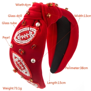 Detailed view of hand-sewn beads, rhinestones and pearls on a red knotted headband