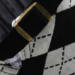 Detailed close-up of retro plaid fabric and bronze metal buckle on the newsboy cap