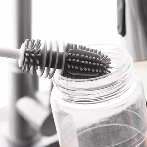 Close-up of gray silicone brush head cleaning a glass bottle in a kitchen setting