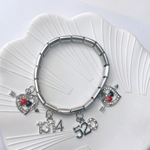 Detail of stainless steel charm bracelet with 520 and 1314 numeric pendants and heart arrow