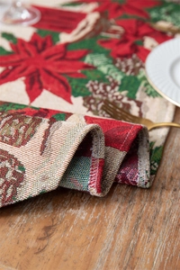 Close-up of woven Christmas table runner with poinsettia, pinecones and candle patterns