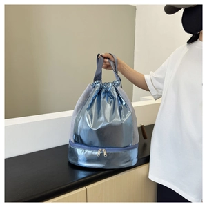 Detail of blue drawstring swim bag featuring a bottom wet-dry compartment and mesh side panels