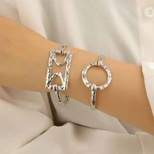Detail of silver alloy cuff bracelets with handmade hammered texture on model's wrist