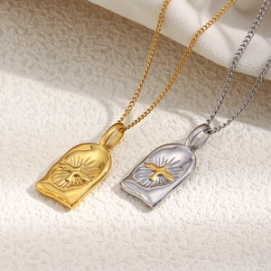Détail des pendentifs croix soleil dorés et argentés sur des colliers en acier inoxydable