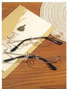 Detail of gold and silver half-rim glasses frames on a vintage rustic wooden surface