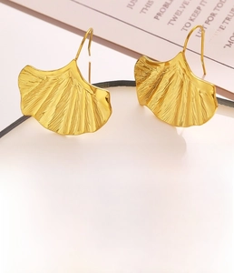 Détail macro des boucles d'oreilles en feuilles de ginkgo dorées avec texture