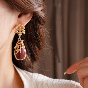 Detail of vintage flower earrings with red teardrop gemstones worn by a model