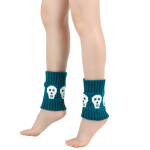 Detailed close-up of teal knitted leg warmers featuring white skull patterns for winter