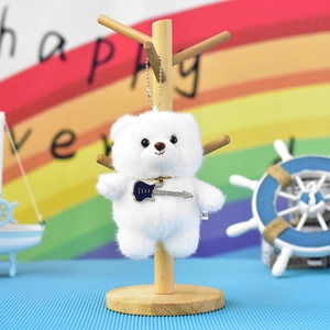 Close-up of a cute white plush bear keychain holding a small blue electric guitar.
