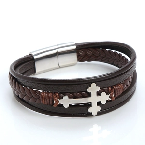 Close-up of brown braided leather bracelet with silver cross and magnetic metal clasp