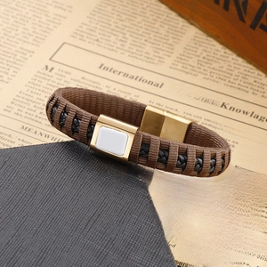 Detail of brown and black braided leather bracelet with gold magnetic clasp and white inlay