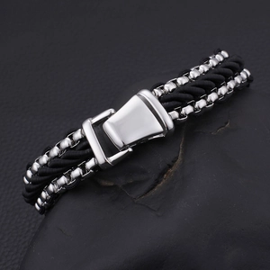 Close-up of multilayer braided black cord bracelet with silver metal clasp on dark stone