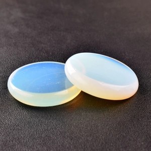 Macro view of polished round opal stones with blue glow on black leather background