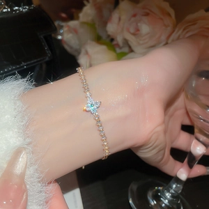 Detail of elegant gold clover bracelet with sparkling cubic zirconia on a woman wrist