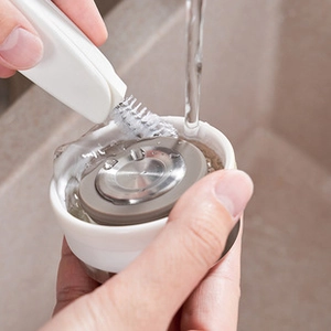 Gros plan d'une brosse de nettoyage blanche frottant un bouchon sous l'eau