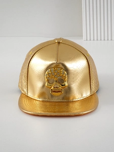Macro shot of gold PU leather baseball cap with textured pattern and rhinestone skull
