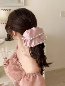 Pink silk scrunchie with white pearl trim shown on hair from a back view perspective