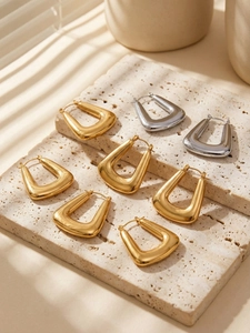 Macro shot of U-shaped gold and silver earrings on stone with natural sunlight shadows
