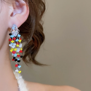Macro detail of long tassel earrings with multicolored heart beads and clear zircon