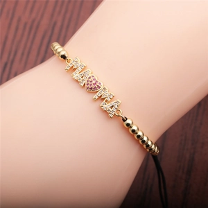 Detail of adjustable golden MAMA bracelet with sparkling zircon heart on female wrist