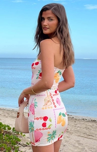 Close-up of strapless summer dress with tropical fruit print against beach background