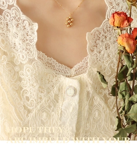 Close-up of a minimalist gold bead necklace paired with delicate beige lace fabric detail