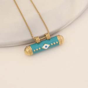Golden cylinder necklace with turquoise enamel devil eye pendant on ceramic plate