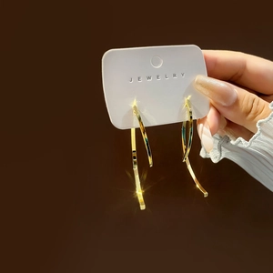 Detailed view of long gold curved metal drop earrings on a jewelry card brandishing elegance