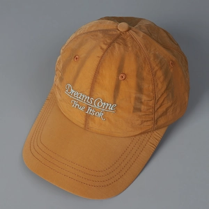 Detail of embroidered 'Dreams Come True' text on yellow quick-dry nylon baseball cap
