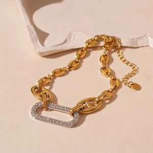 Bracelet chaîne grain de café doré avec pendentif ovale pavé de zircons sur fond pierre