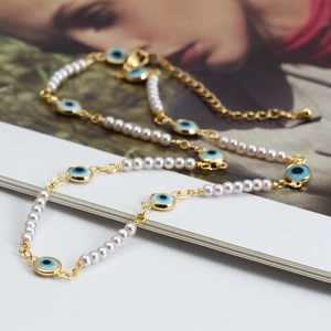 Detail of gold evil eye necklace with white pearls and blue enamel nazar charms