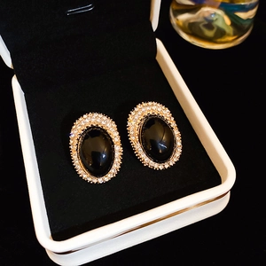 Close-up of vintage oval stud earrings with black center and pavé crystals in a jewelry box