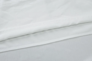 Vue détaillée de la couture et de la texture lisse du tissu sur l'ourlet de la robe blanche