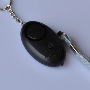 Close-up of black personal security alarm with silver keychain and braided grey lanyard