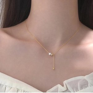 Elegant gold Y-shaped pearl necklace with long drop chain on model wearing white blouse