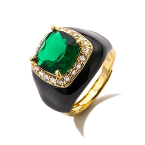 Detailed macro of gold plated ring featuring green emerald-cut stone and black enamel inlay