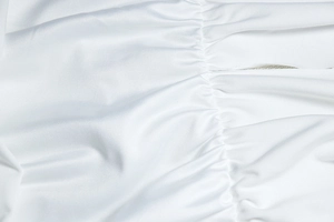 Close-up of white fabric texture showing detailed pleated and ruched stitching details