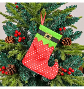 Close-up of elf boot Christmas stocking with gold bell hanging on a festive pine tree