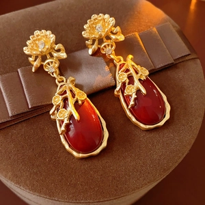 Macro shot of vintage gold flower earrings with red oval gems and clear stones