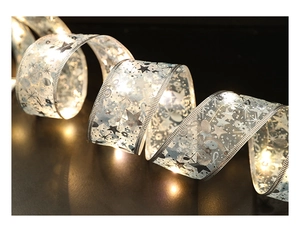 Macro shot of silver silk Christmas LED ribbon with warm white lights and golden printing