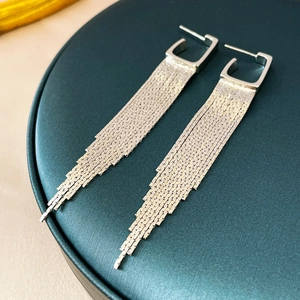 Detail of silver geometric fringe earrings with dangling metal chains on velvet tray
