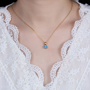 Close-up of minimalist gold 925 silver necklace with blue cubic zirconia birthstone