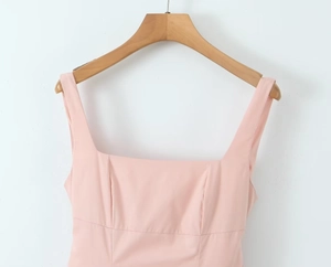 Detail of pink dress featuring a square neckline and wide shoulder straps on a hanger