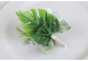 Detail of the back of a bridal boutonniere showing the secure green safety pin and ribbon